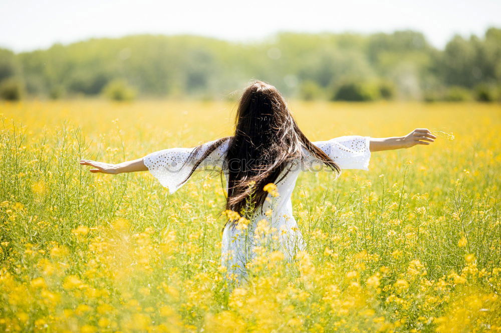 Similar – Image, Stock Photo Beautiful young woman enjoying the warm sun in the nature. Attractive girl is in yellow green meadow full of flowers. With head up and eyes closed she is happy about spring or summer.