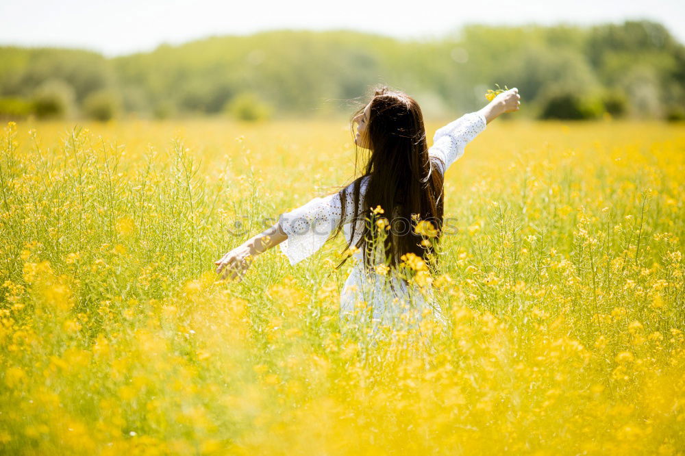 Similar – Image, Stock Photo Beautiful young woman enjoying the warm sun in the nature. Attractive girl is in yellow green meadow full of flowers. With head up and eyes closed she is happy about spring or summer.