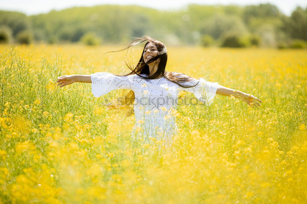 Similar – Image, Stock Photo Beautiful young woman enjoying the warm sun in the nature. Attractive girl is in yellow green meadow full of flowers. With head up and eyes closed she is happy about spring or summer.