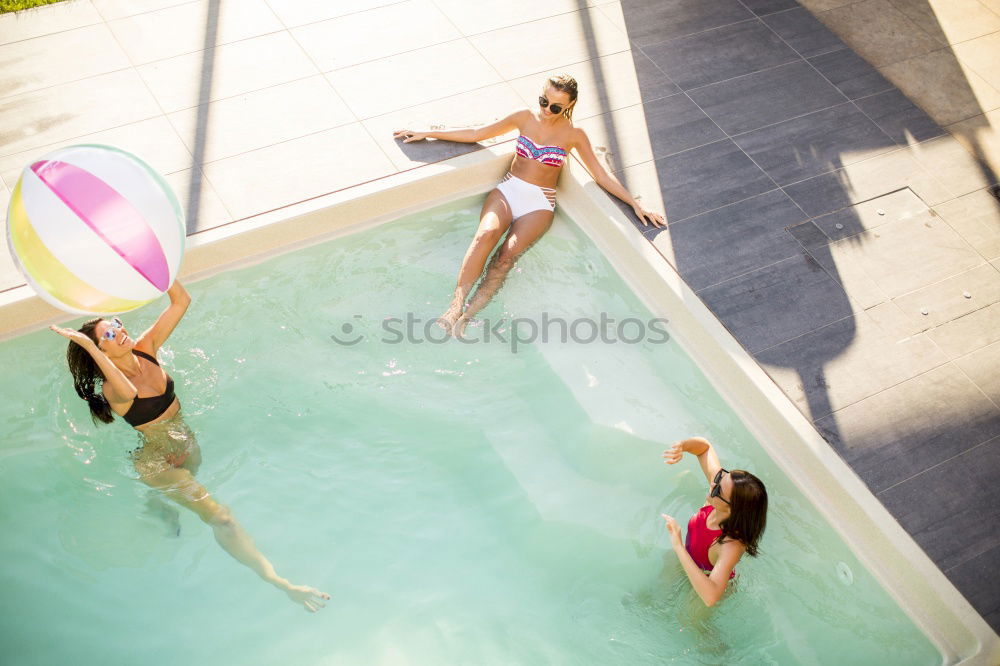 Two young women in swimsuits relaxing in the swimming pool