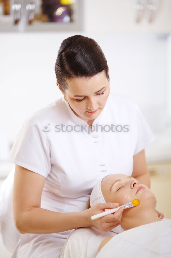 Professional cosmetician applying a facial mask with cosmetic brush