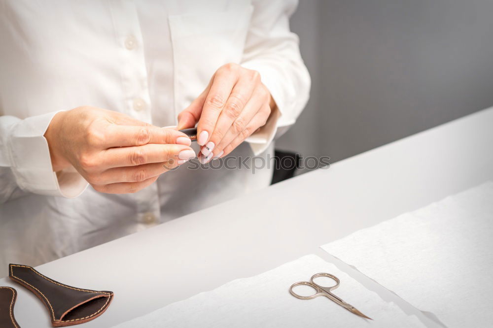 Close up on woman’s hands sewing needle and thread. Old woman working wasted hands .Tailor sewing some fabric. Details, low light, moody