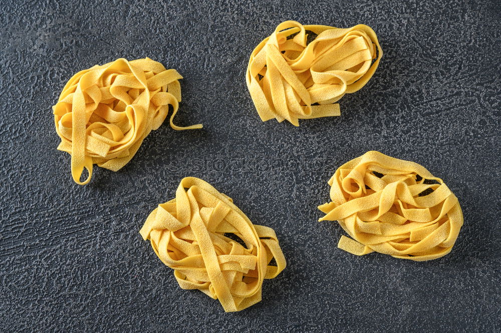 Raw tagliatelle on dark table