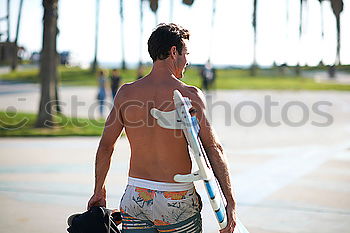 Similar – Man with tattoos holding skateboard at shore. Back view.