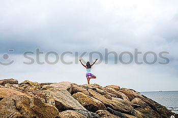 Similar – Girl with arms raised standing on the cliff