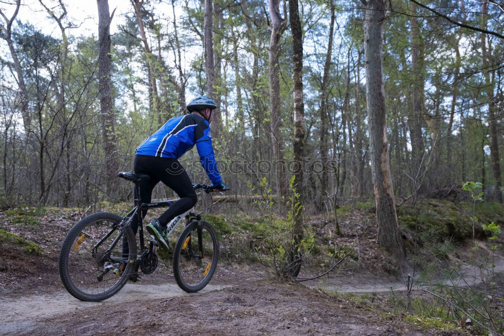 Similar – Biker in Jeans und kariertem Hemd springt mit dem Fahrrad die MTB-Strecke hinunter