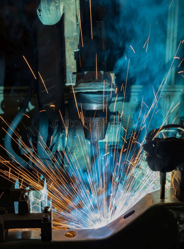 Mechanic man welding metal material in garage.