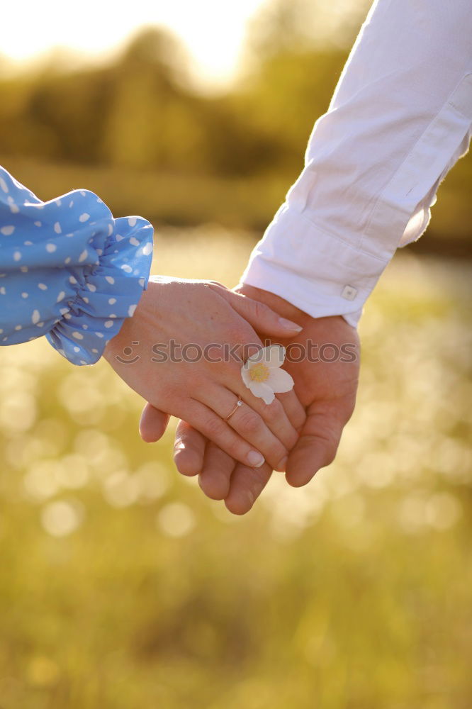 Baby girl holding finger of senior man hand