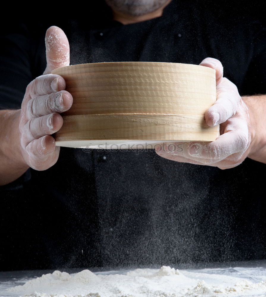 round wooden sieve in male hands