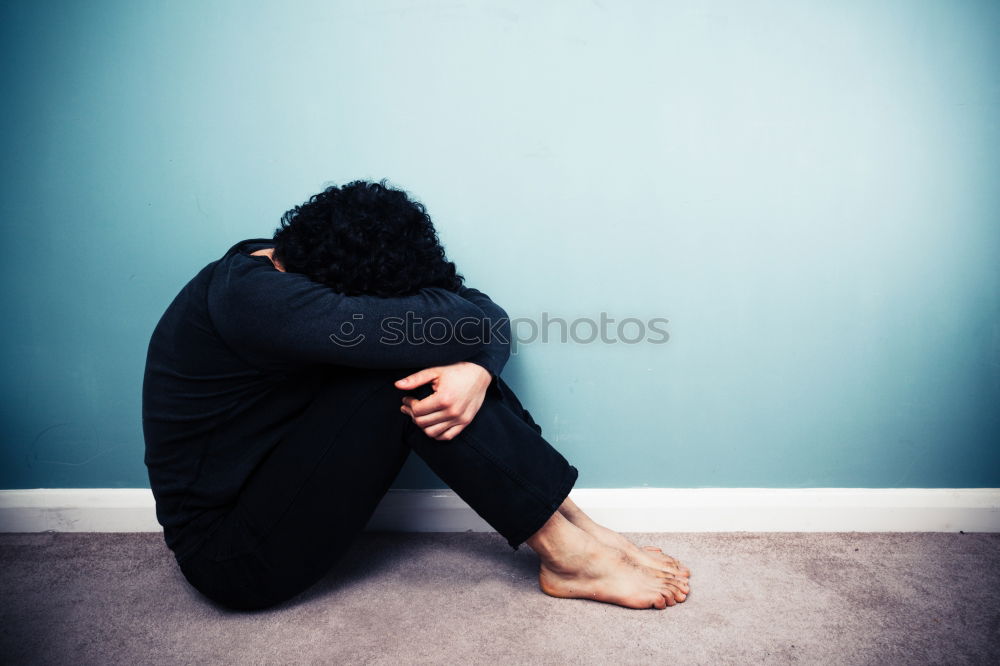 Similar – one sad woman sitting near a wall and holding her head in her hands