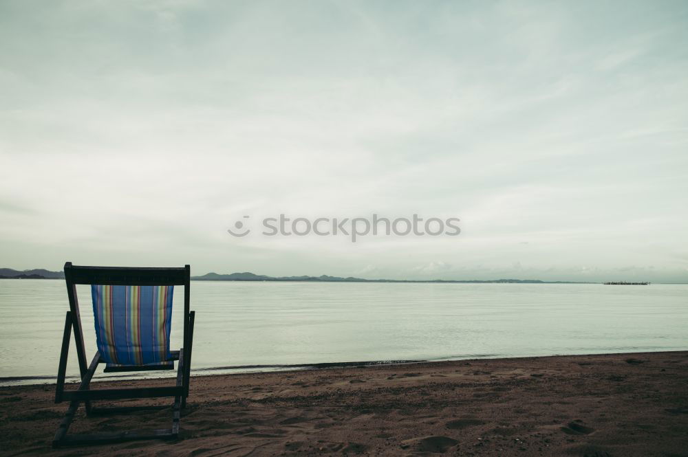 Similar – Rear view of a woman sitting on a wooden bench and looking at a lake