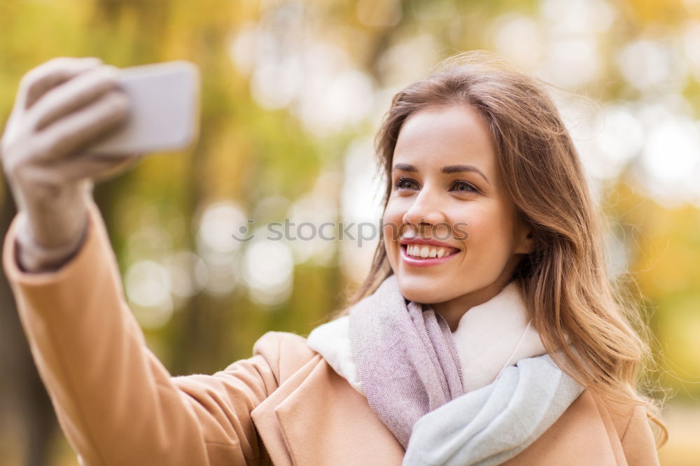 Young happy woman with green jacket taking selfie with her smartphone on the beach at sunset