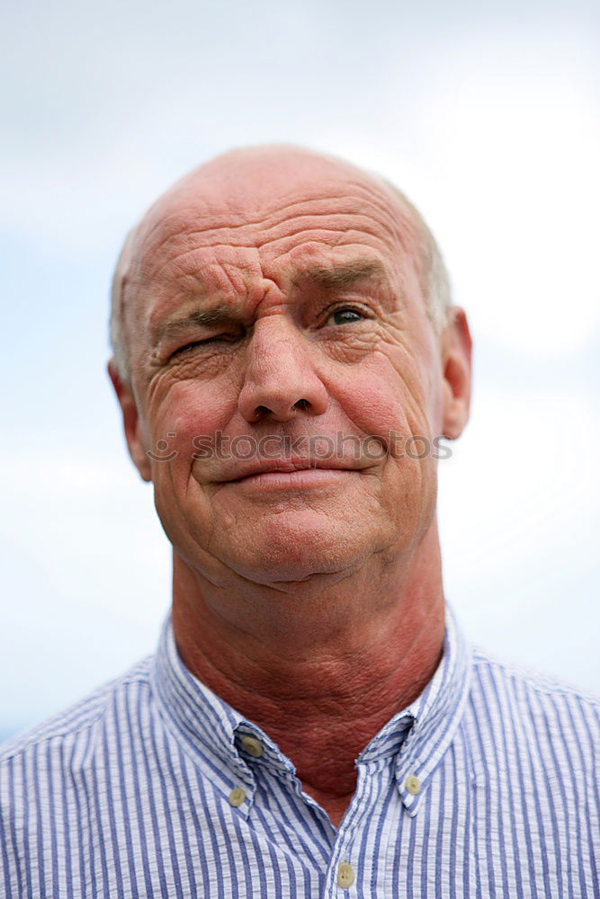 Similar – Portrait of a senior citizen with short grey hair and three-day beard in front of a blue-grey sky