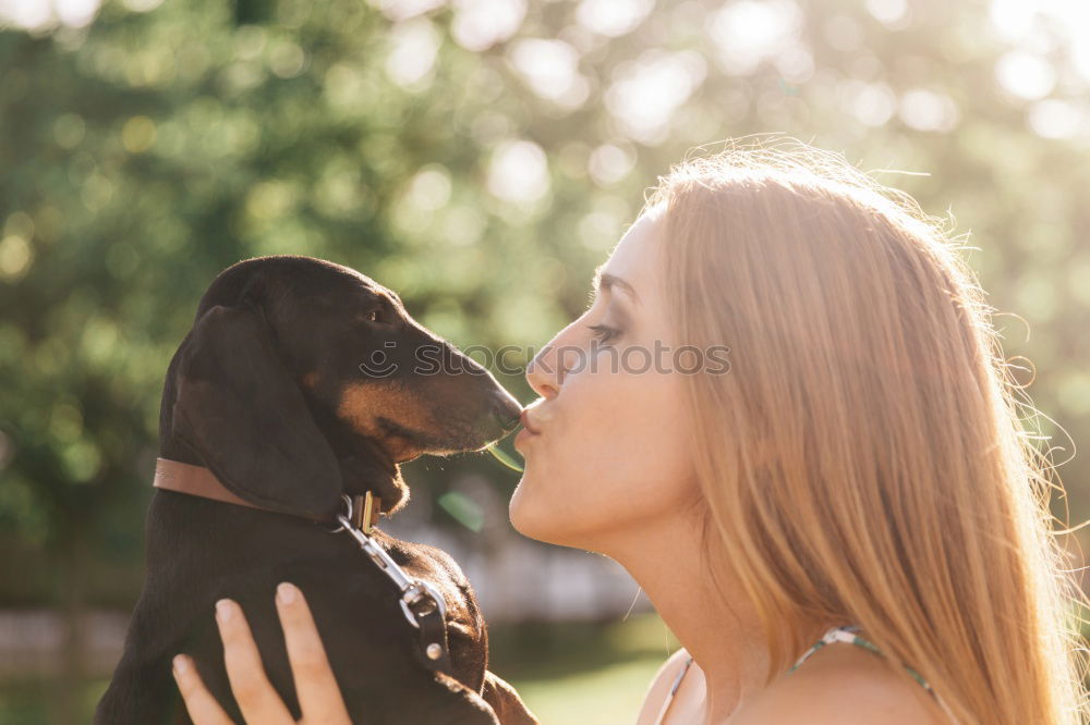 young woman with her dog at the park. she is kissing the dog. autumn season