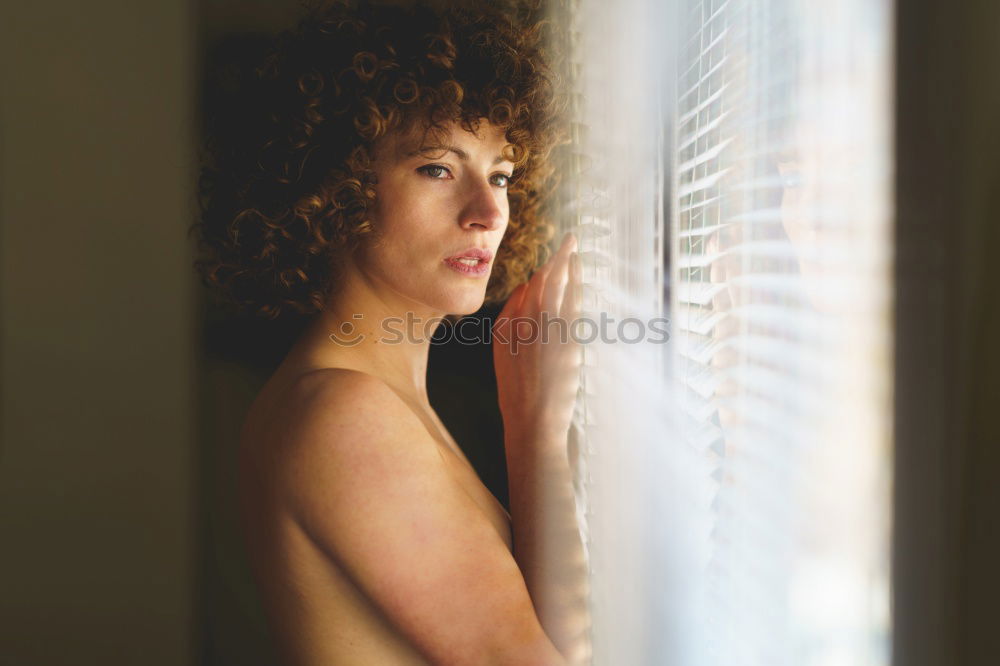 Similar – young, redheaded woman with curls looks out of the balcony window