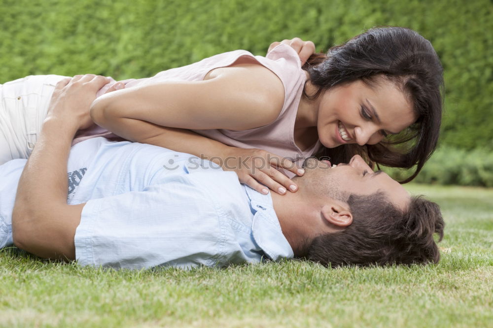 Happy smiling couple laying on green grass