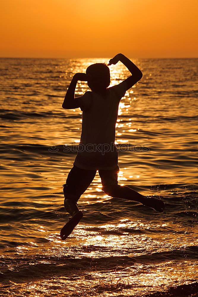 Father and son playing on the beach at the sunset time.