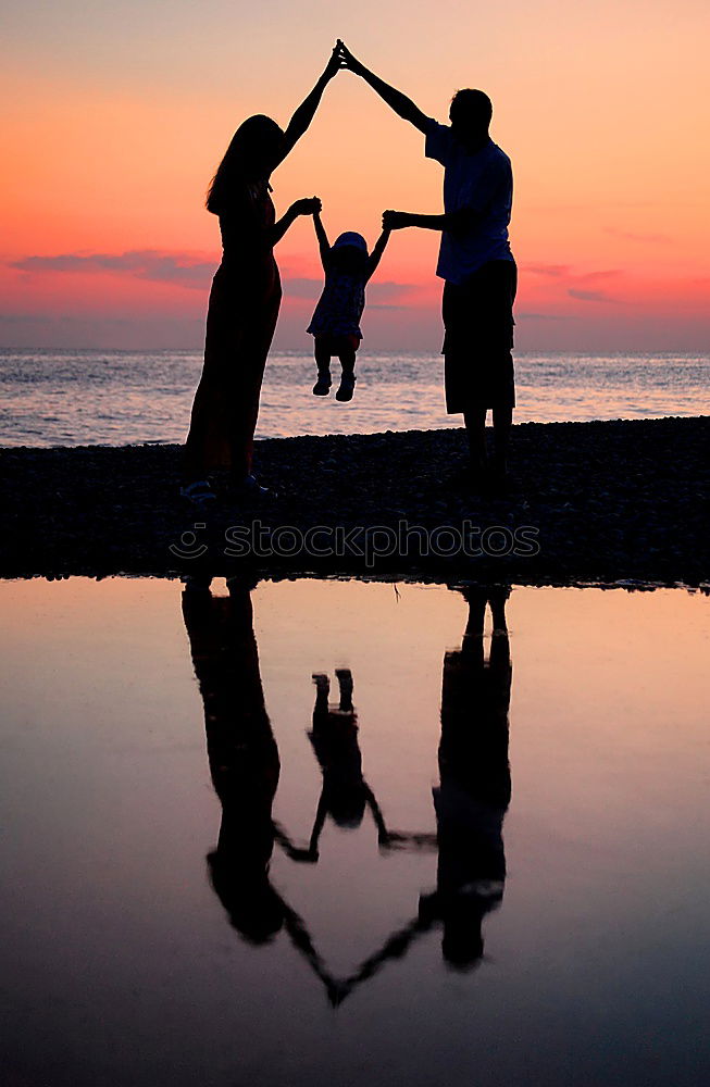 Mother and son holding hands on a beach at sunset