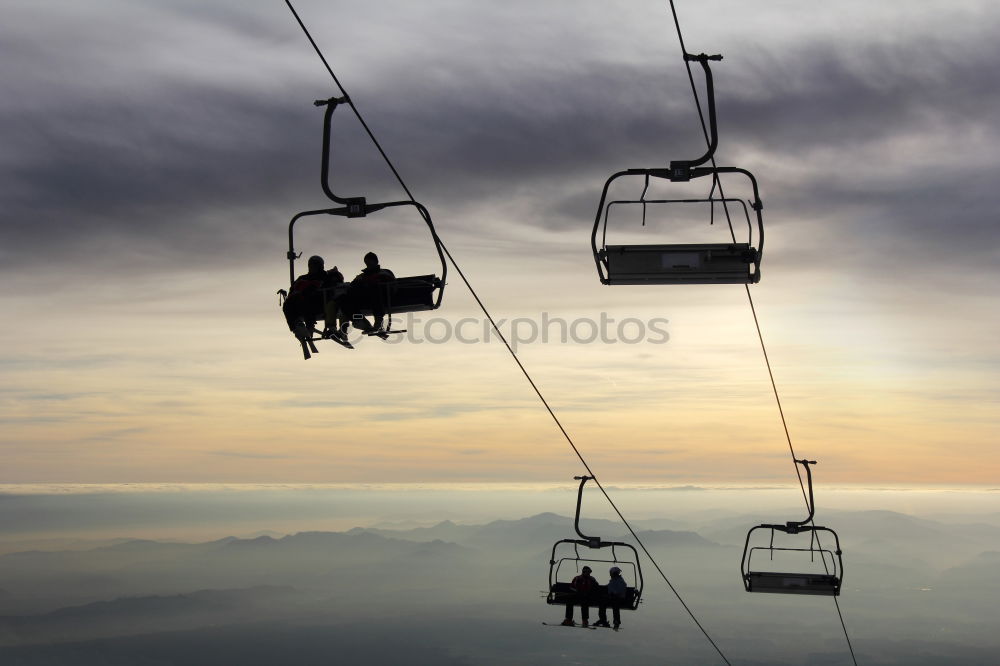 Chairlift with empty 2-seater chair and view of snow-free hill country