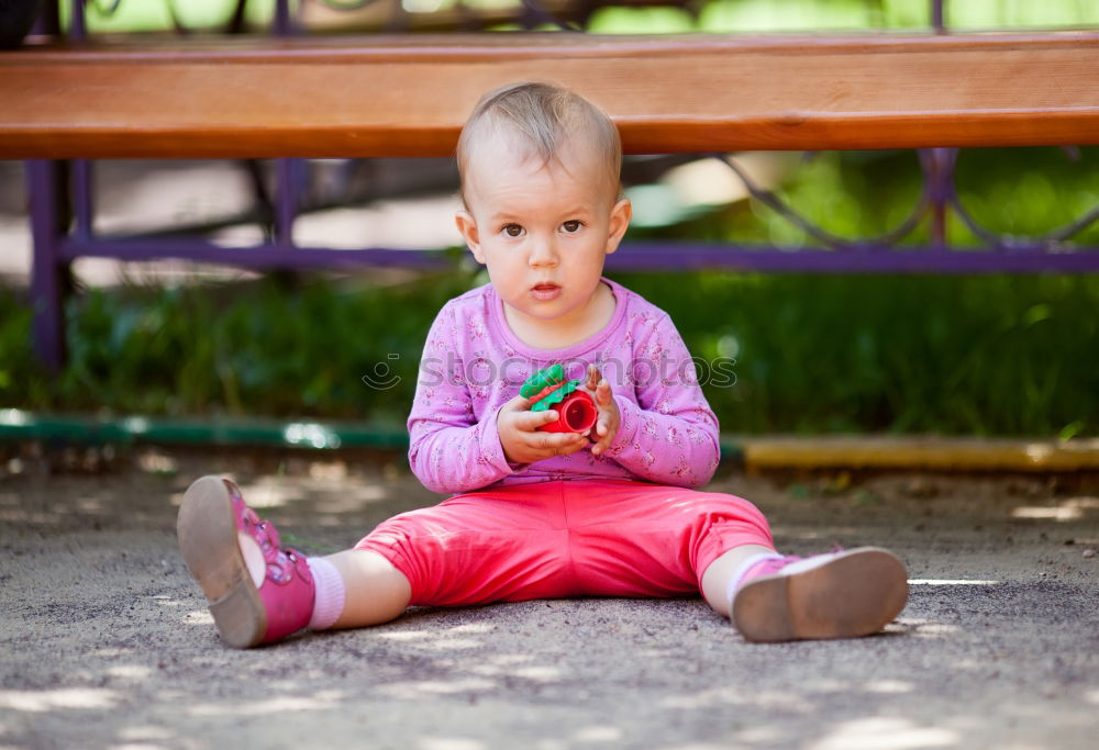 Image, Stock Photo Small baby playing with toy sitting on the ground in the park and looking to the camera