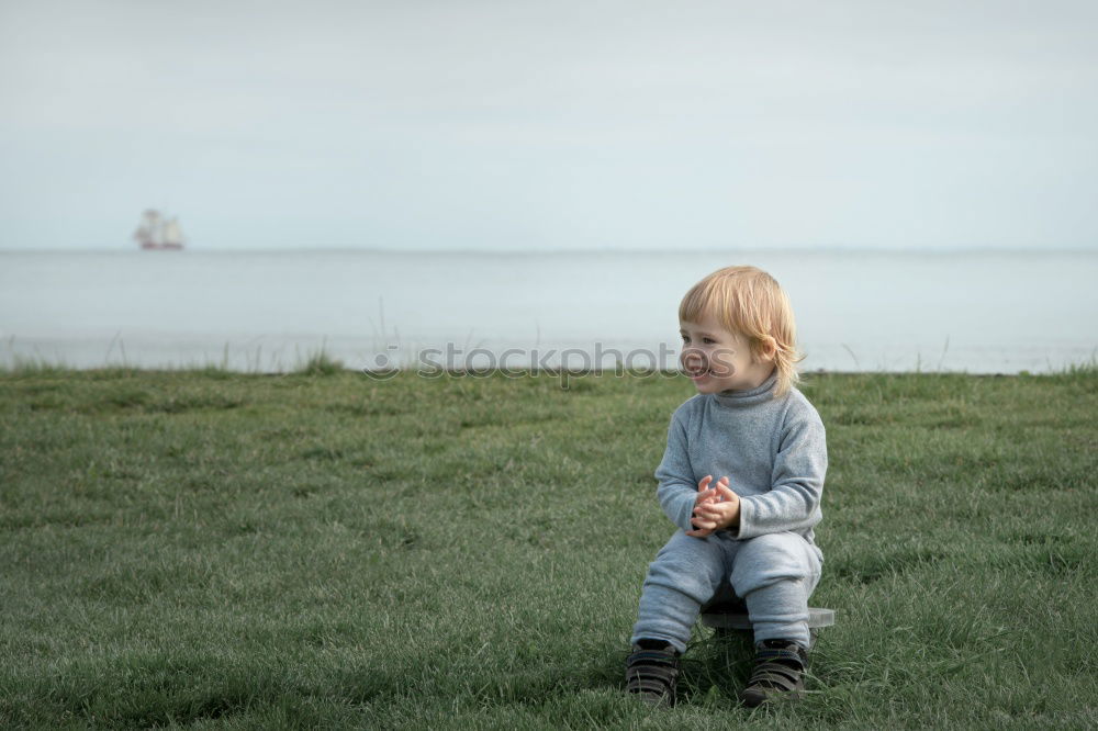 Similar – Child sitting by the sea with a view of a jetty