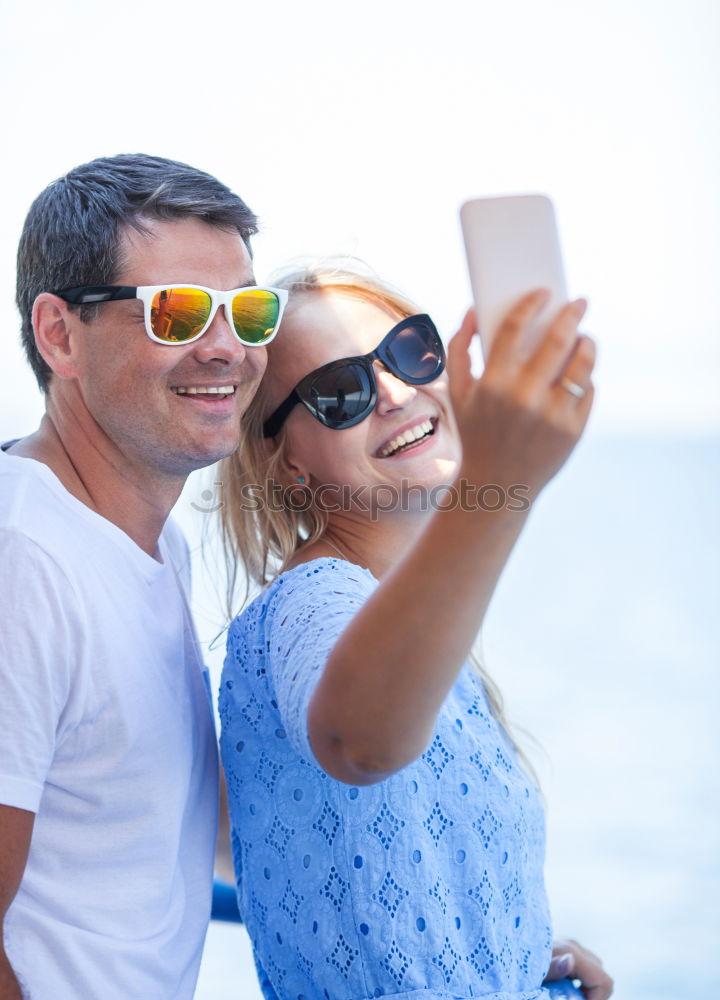 Similar – Happy young man and woman in fashionable sunglasses taking cellphone selfie on background of defocused blue sea. Vacation photos