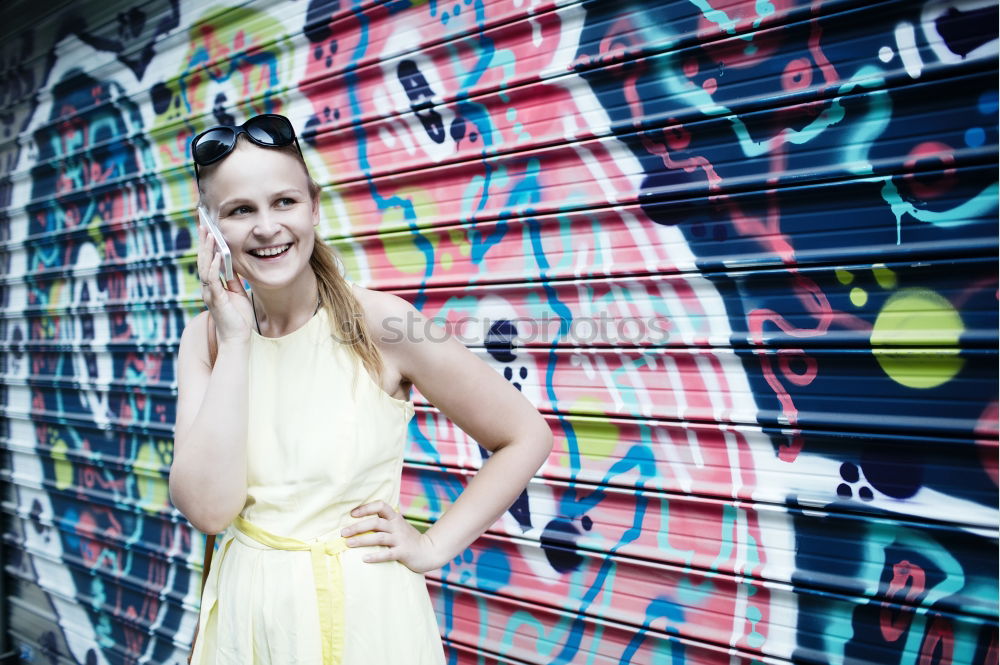 Image, Stock Photo Smiling woman in yellow dress standing and chatting on her smart phone in front of graffiti painted on corrugated iron