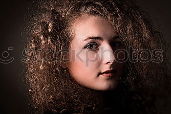 Young natural woman with freckles and wild curly hair looking at the camera