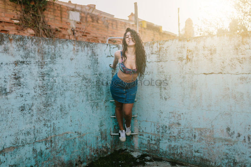 Similar – Young woman sitting leaning against a wall in the shade