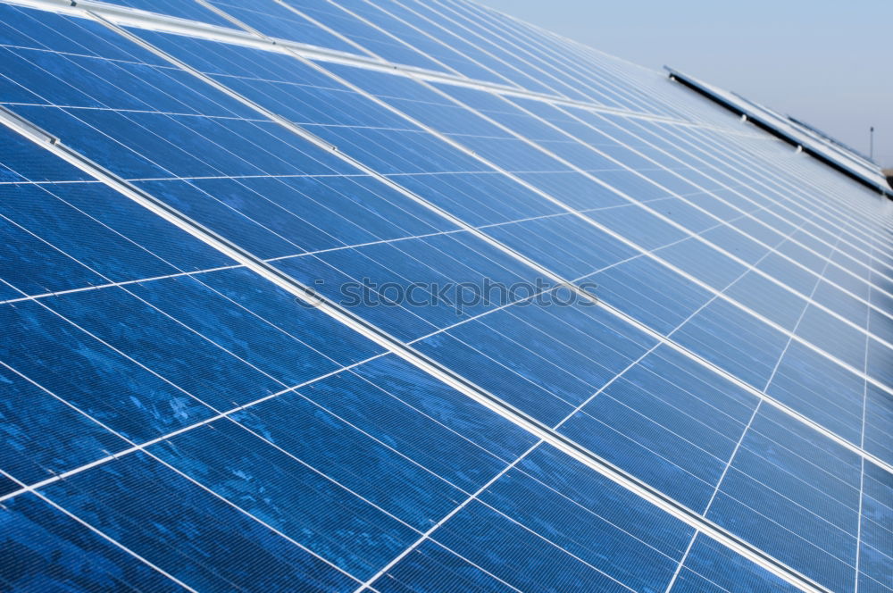 Photovoltaic panels in a solar power plant over a blue sky.