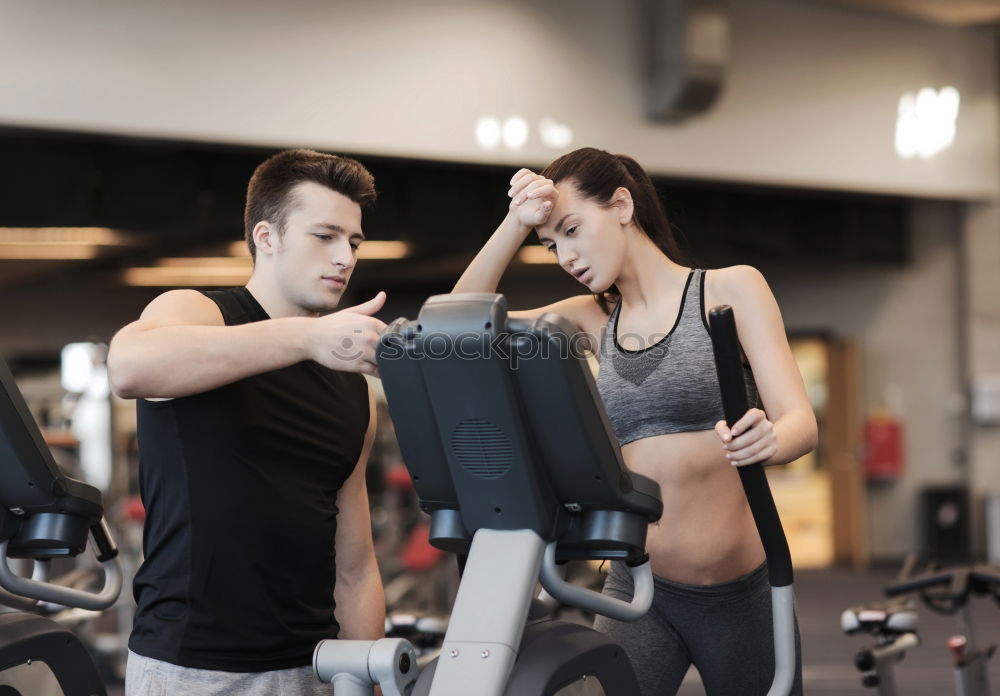 Personal trainer helping young woman lift weights