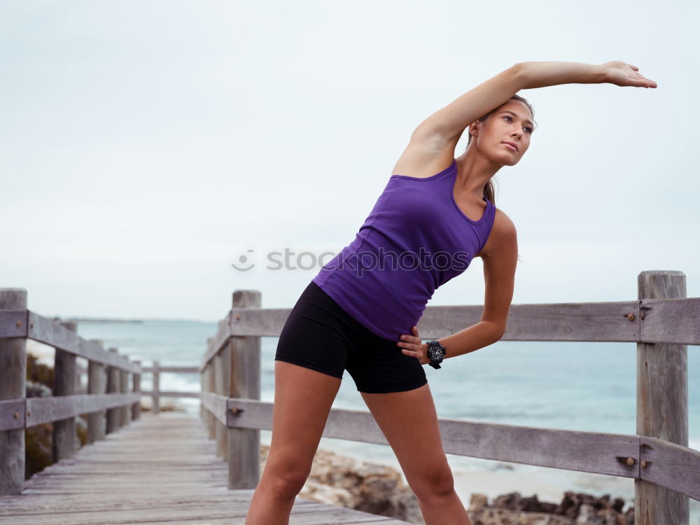 Fit female athlete drinking water after workout on beach