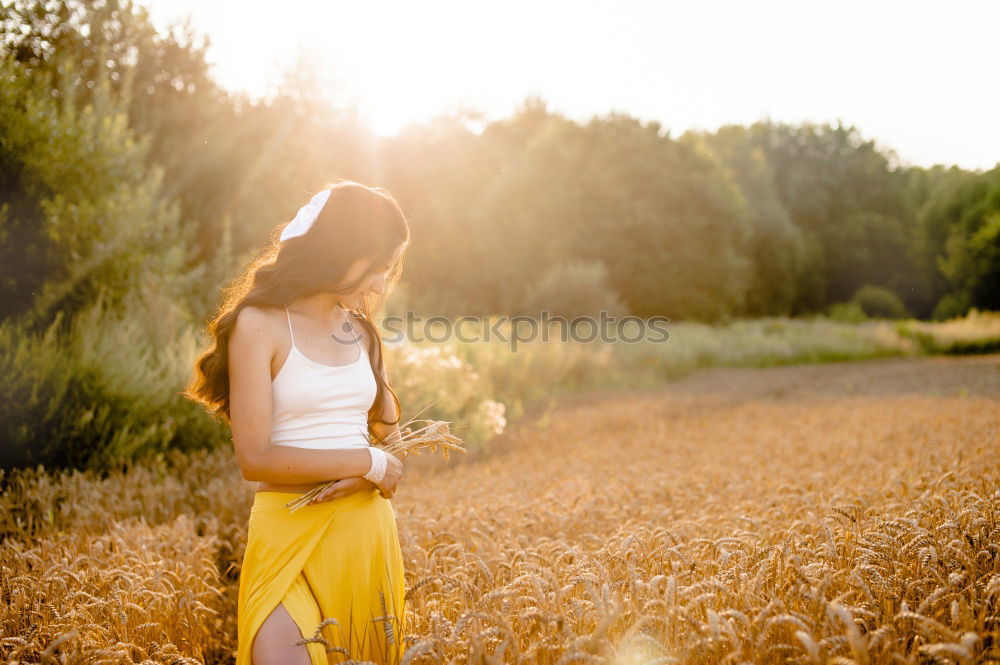 Image, Stock Photo Thoughtful young woman with bowed head on yellow meadow. Attractive girl with bowed head on a meadow of flowers in yellow to the horizon in the sunshine in spring or summer. Photo of a series.