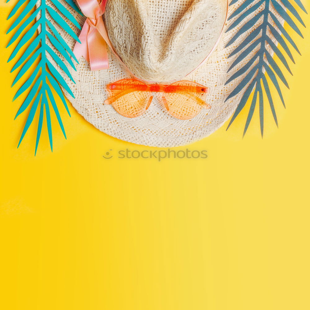 Straw hat with sunglasses and tropical leaves