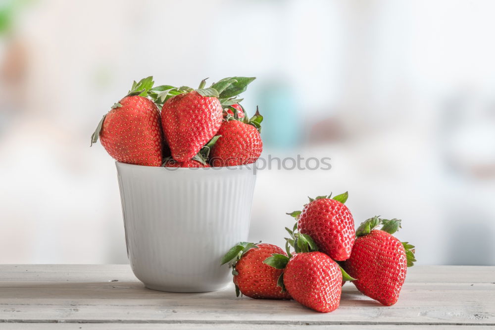 Strawberries in a bowl on a white wooden table