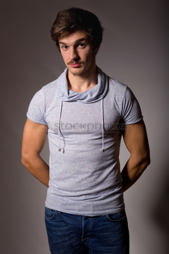 Young man standing in urban background with modern hairstyle.