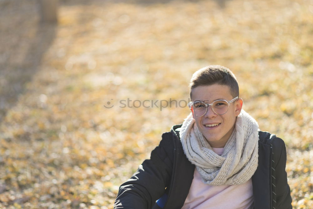 Stylish smiling teenager sitting on the ground in a city park