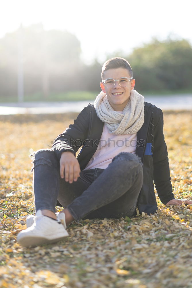 Similar – Stylish smiling teenager sitting on the ground in a city park