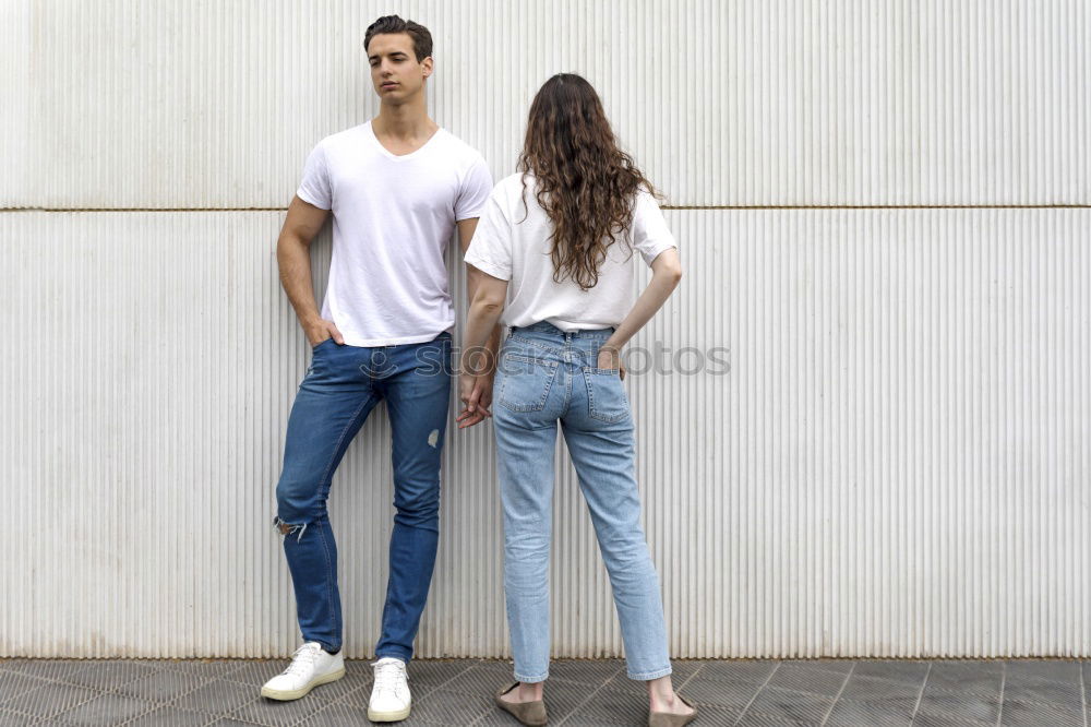 Side view Happy couple in love jumping against grey wall.