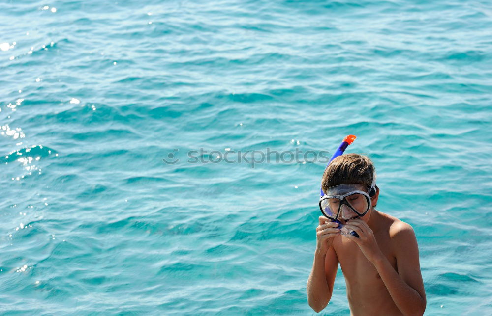 Little boy floating on the sea with transparent water