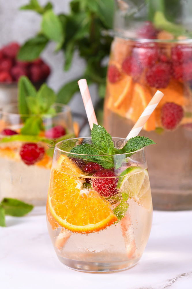 Two glasses of soft drink with honey- and watermelon, rosemary, ice cubes and drinking straw