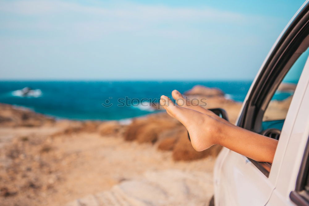 Unrecognizable man resting feet up sitting on the car