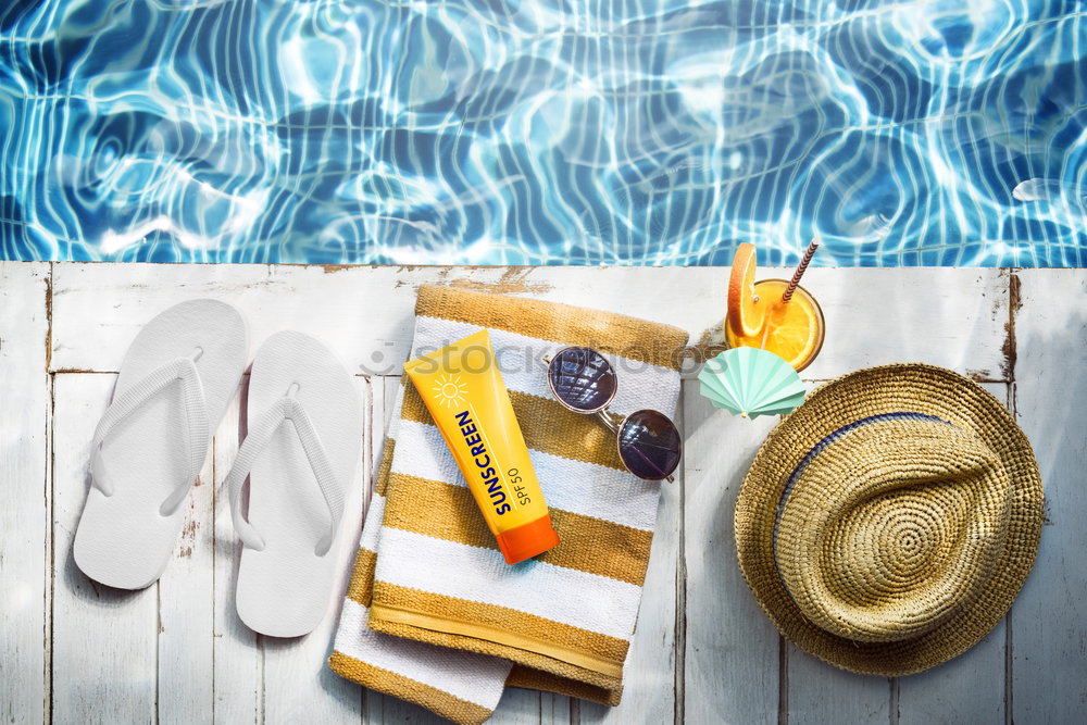 flat lay with woman’s sandals and hat front of the pool
