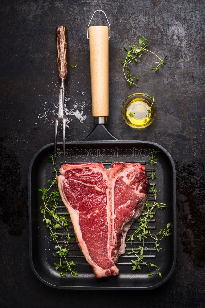 Image, Stock Photo T-bone steak on grill pan with meat fork, oil and spices