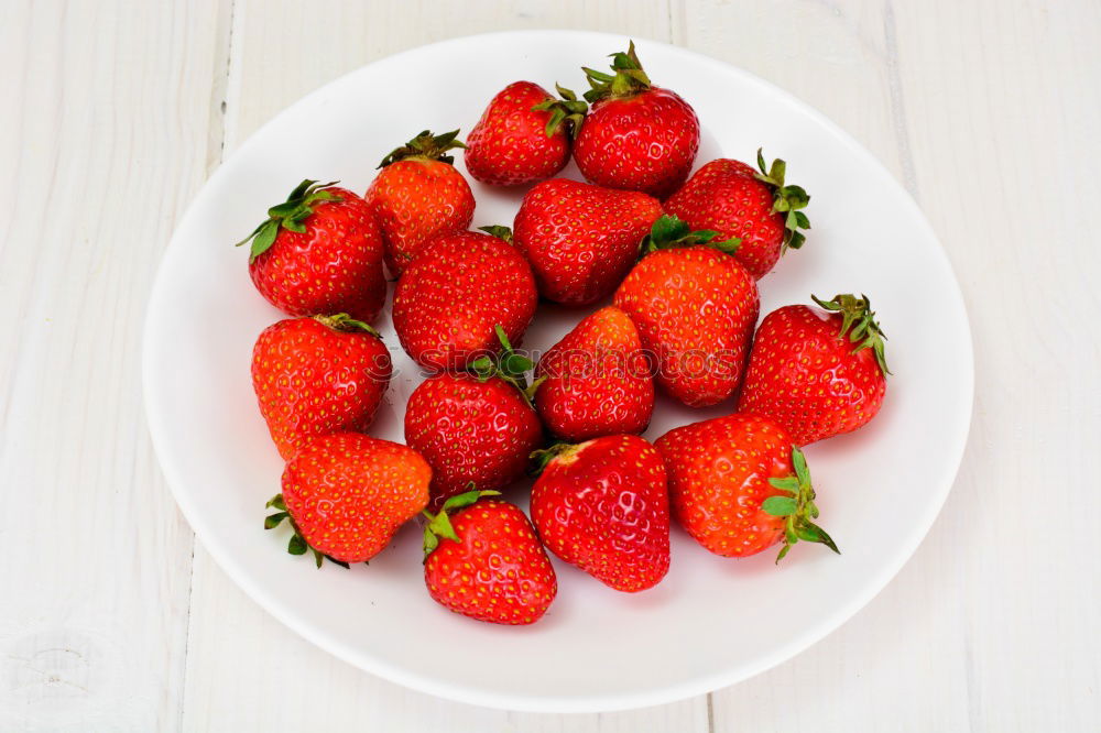 Strawberries whole and cut on a white wooden table