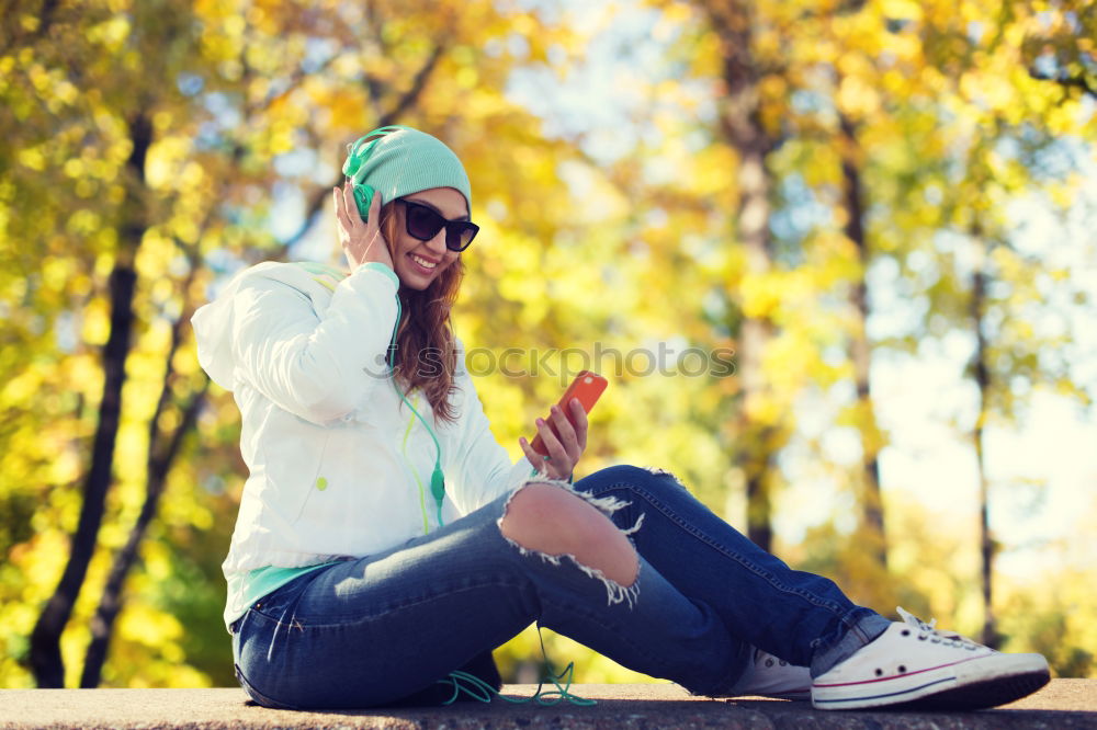 Similar – boy sitting on ground leaning on a wall, taking a selfie