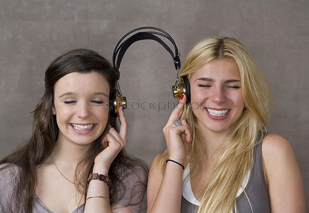 Similar – Two happy teenage girls lying on the grass sharing headphones to listen to music