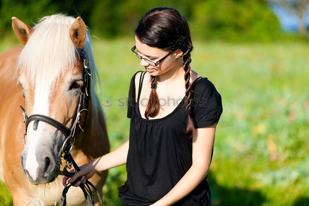 Young dark-haired curly woman with horse in stable