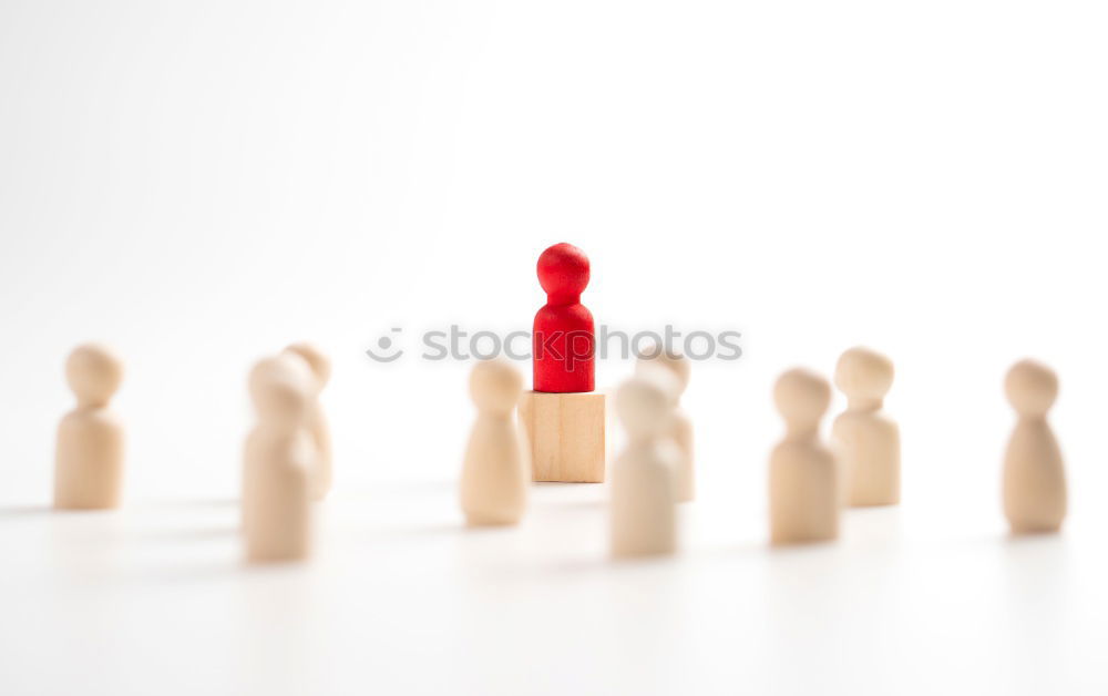 Single red toy figure in front of a row of black toy figures