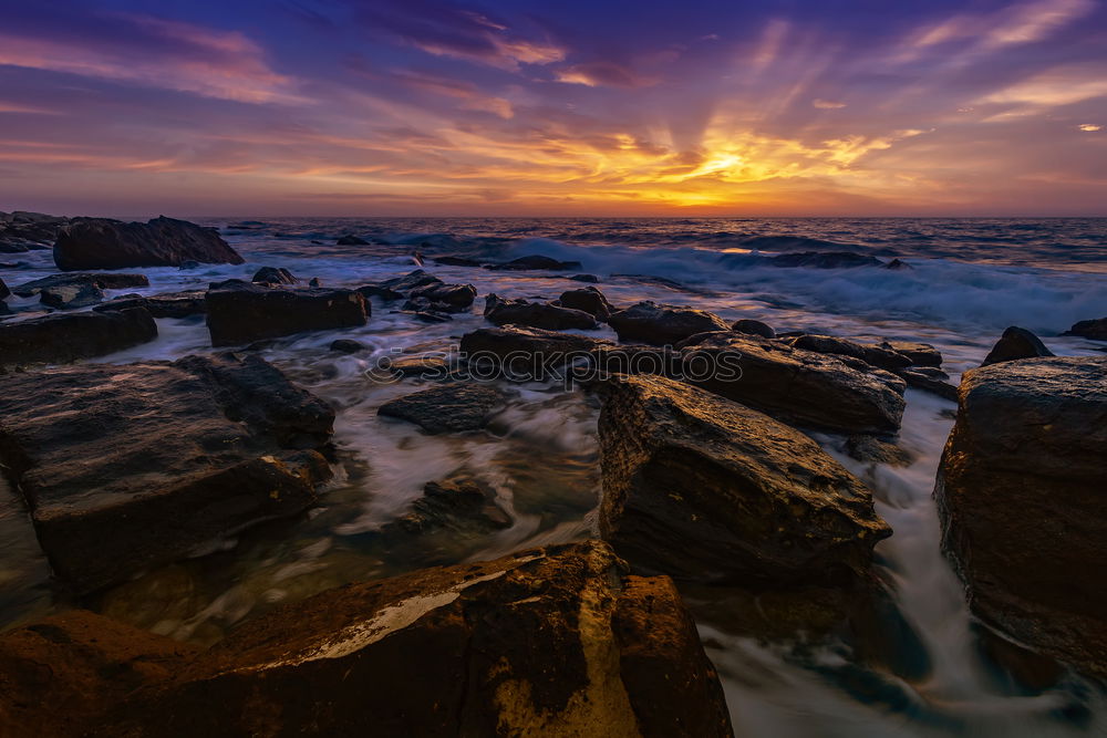 Similar – Sea crashes light waves into rocky bay, long exposure